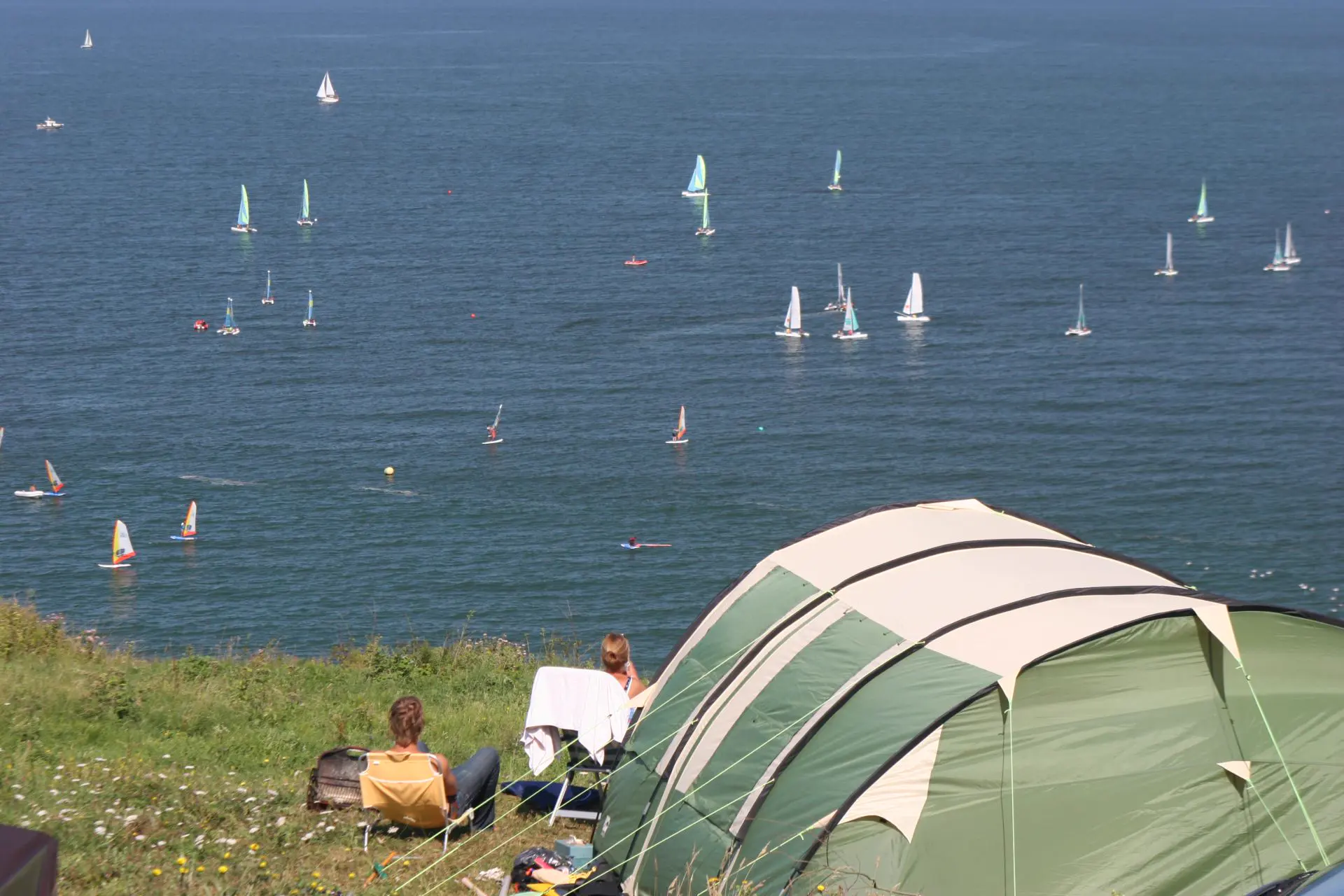 Une tente du camping au-dessus de la mer, des voiliers au large