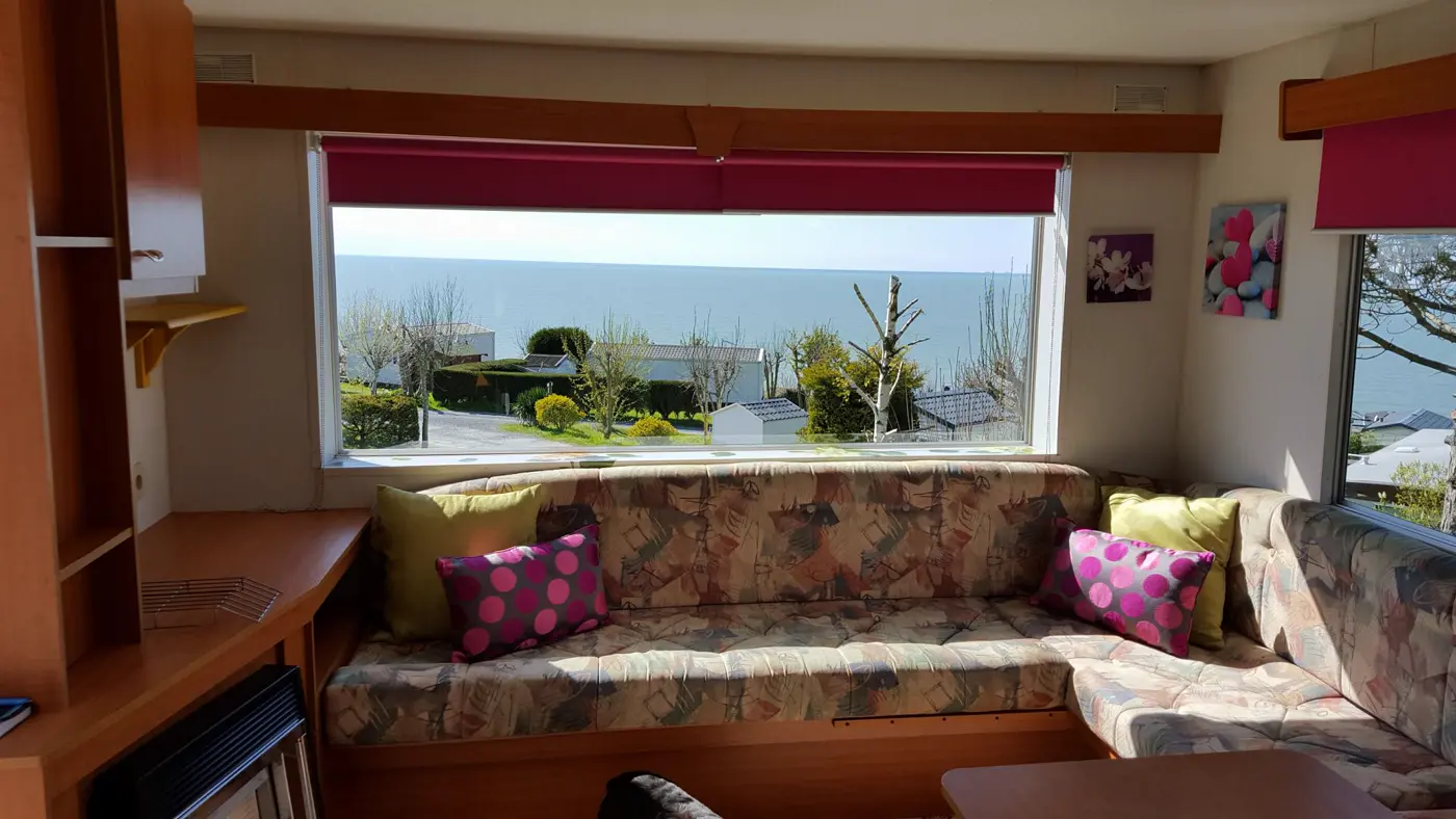 Le salon d'un mobil-home, la mer par la fenêtre